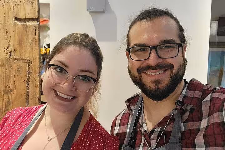 Two smiling participants wearing aprons in a Florence gelato and biscotti making class.