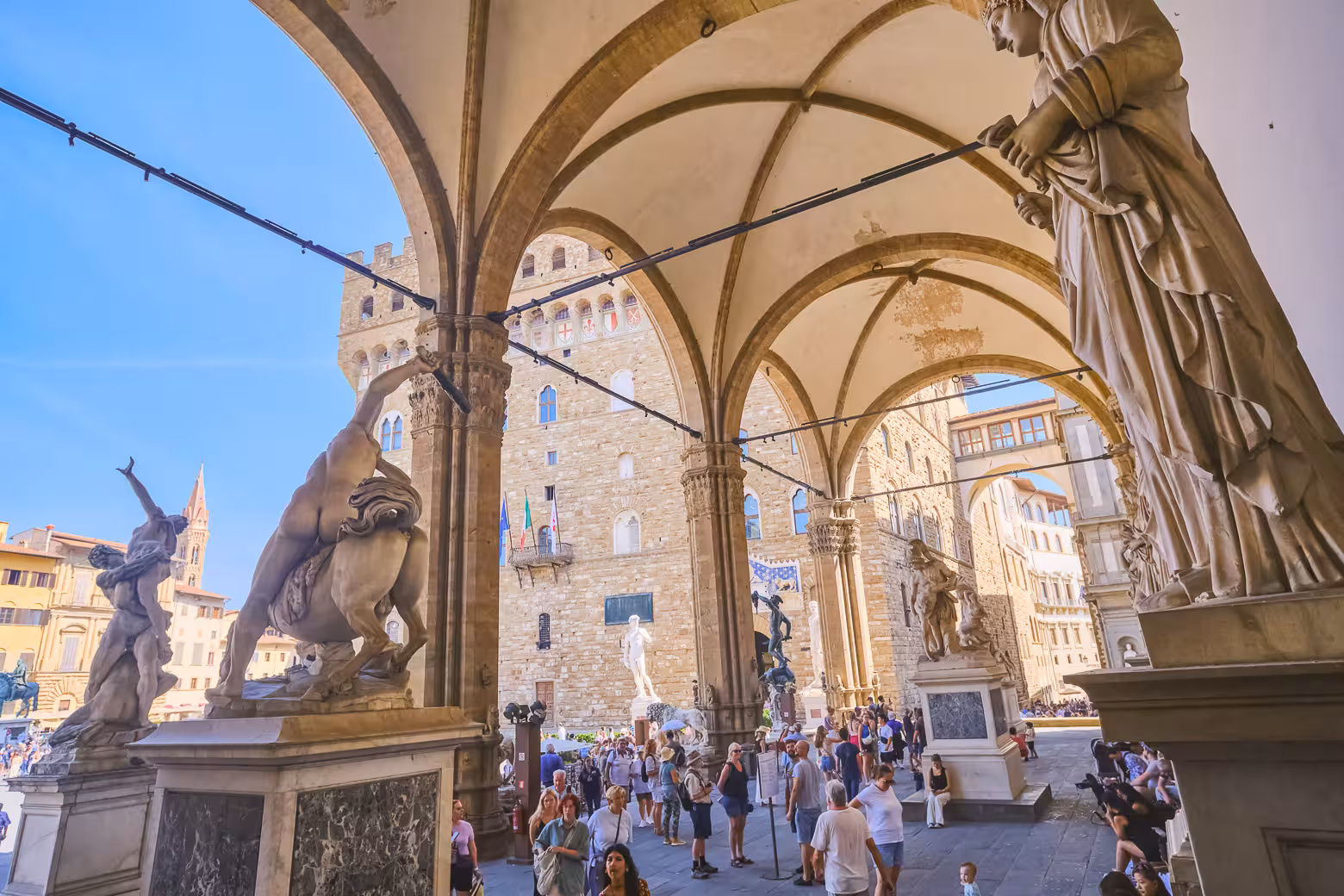 Visitors admire sculptures under the arches of Loggia dei Lanzi in Florence, a highlight of the Accademia Gallery tour.