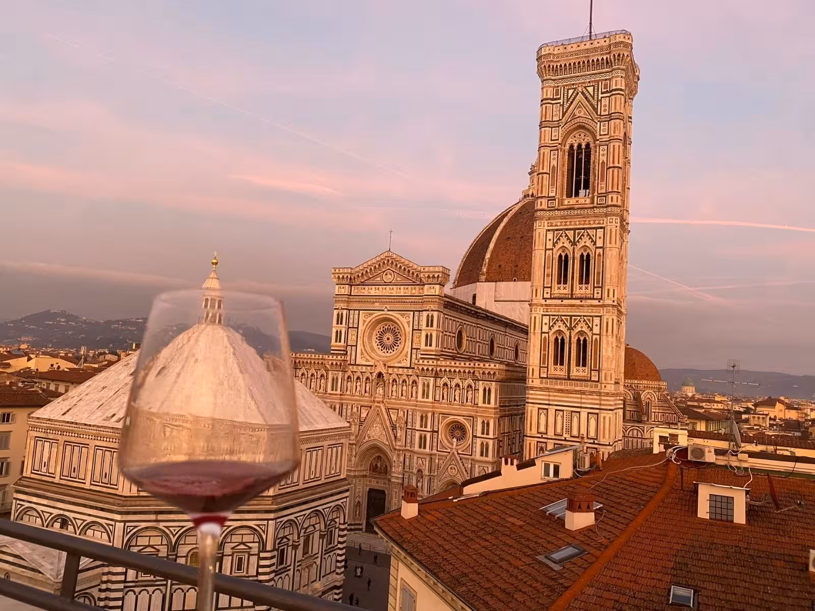 Rooftop wine glass against the backdrop of Florence's iconic cathedral at sunset, ideal for a unique tasting tour.