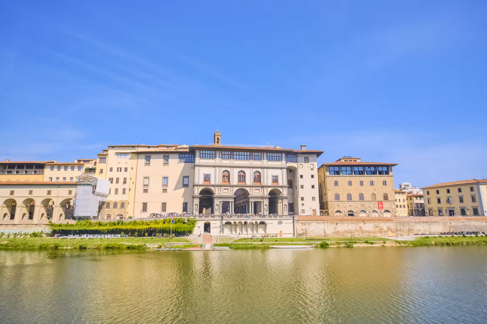 View of Florence's historic Uffizi Gallery along the Arno River on a sunny day.