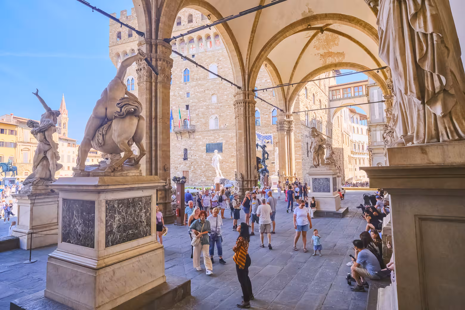 Visitors explore Loggia dei Lanzi's stunning sculptures during a guided Florence small group tour.