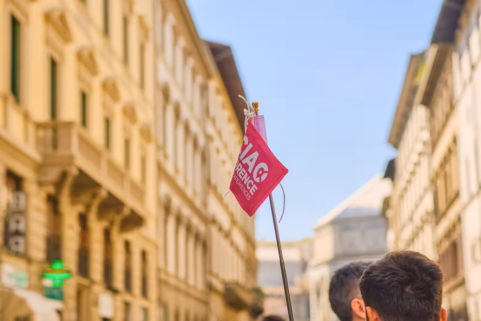 Tour guide holding a pink flag leads a small group through the historic streets of Florence on a monolingual tour.