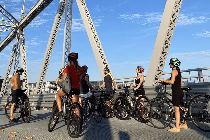 Cyclists pause on an iconic Florianopolis bridge, capturing history and views on their street food and photography tour.