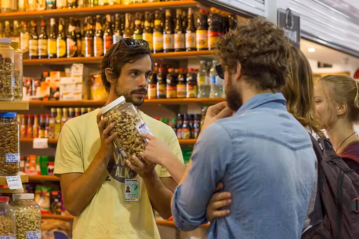 Tour guide explaining local spices and nuts to tourists at a vibrant Florianopolis market on a walking tour.