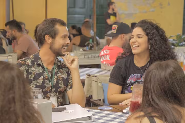 Tourists enjoying local cuisine and lively conversation at a Florianopolis restaurant during a walking tour.
