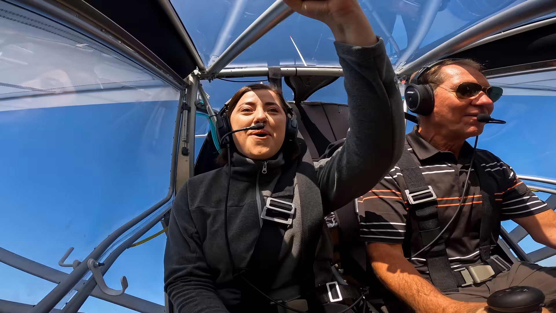 Passenger and pilot in Flying Buggy ultralight cockpit with headsets, enjoying open-air scenic flight