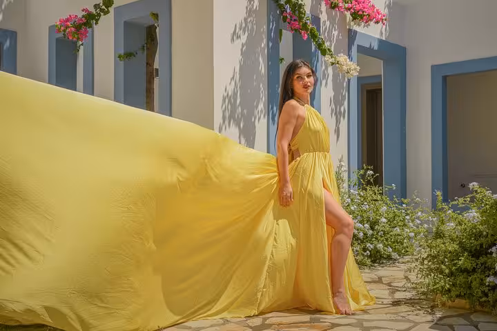 Graceful flying dress photoshoot with a flowing yellow gown amidst floral surroundings in Hersonissos.