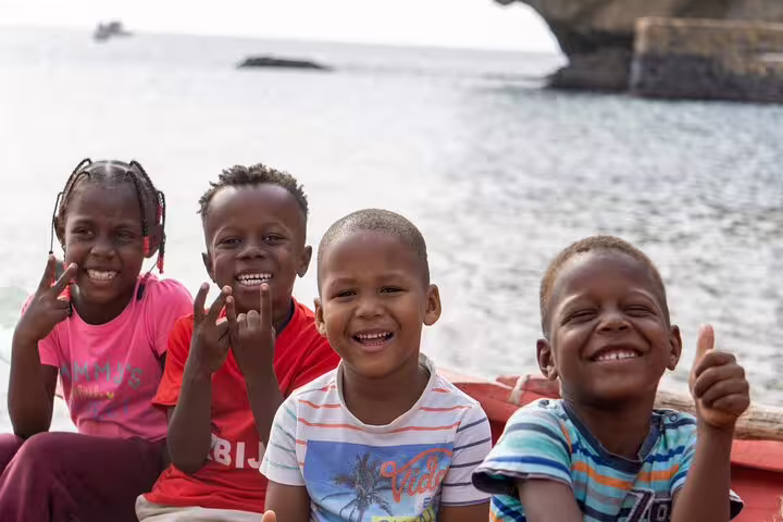 Joyful children smiling by the sea, reflecting the vibrant community spirit of Fogo Island.