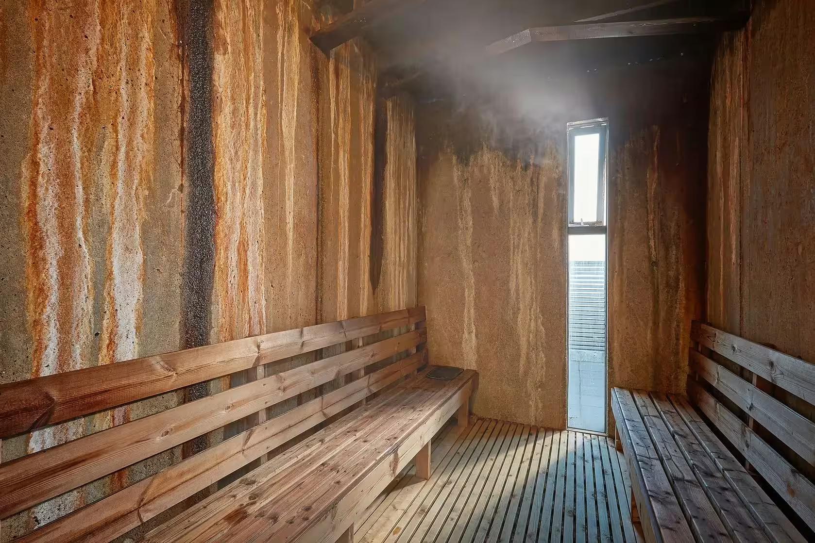 Steam-filled wooden sauna interior with mineral-streaked walls at Fontana Spa Iceland