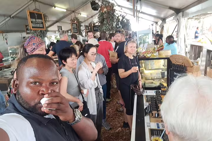 Enthusiastic crowd enjoying diverse flavors at a bustling food market during a 3-hour culinary tour.