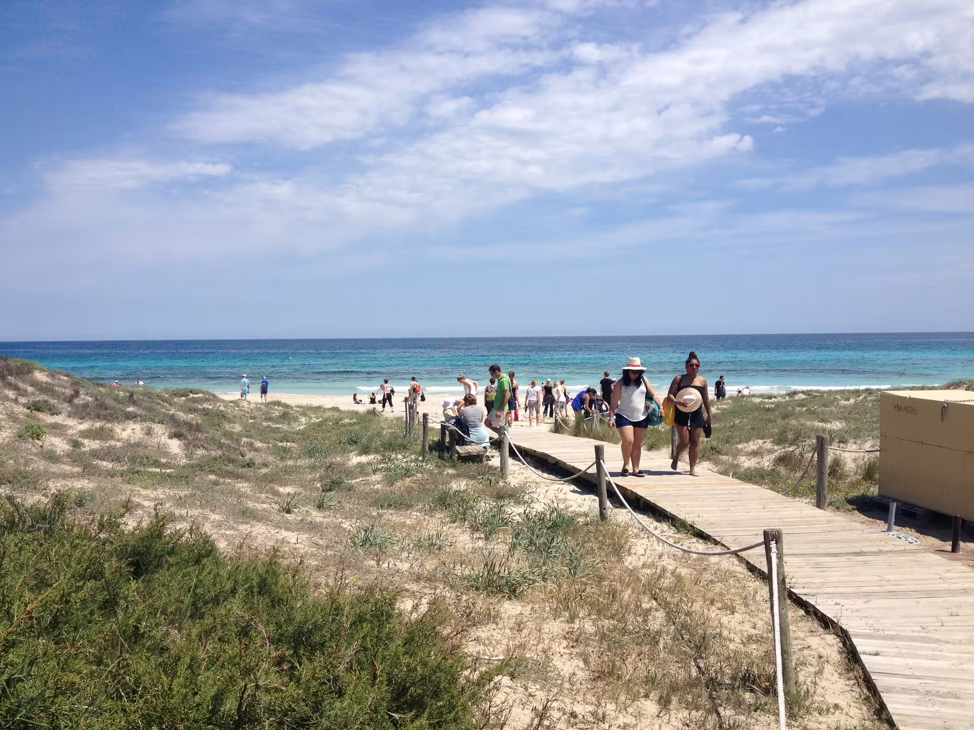 Wooden boardwalk to a Formentera beach on Ibiza day trip by bike, with transfer and ferry to turquoise waters