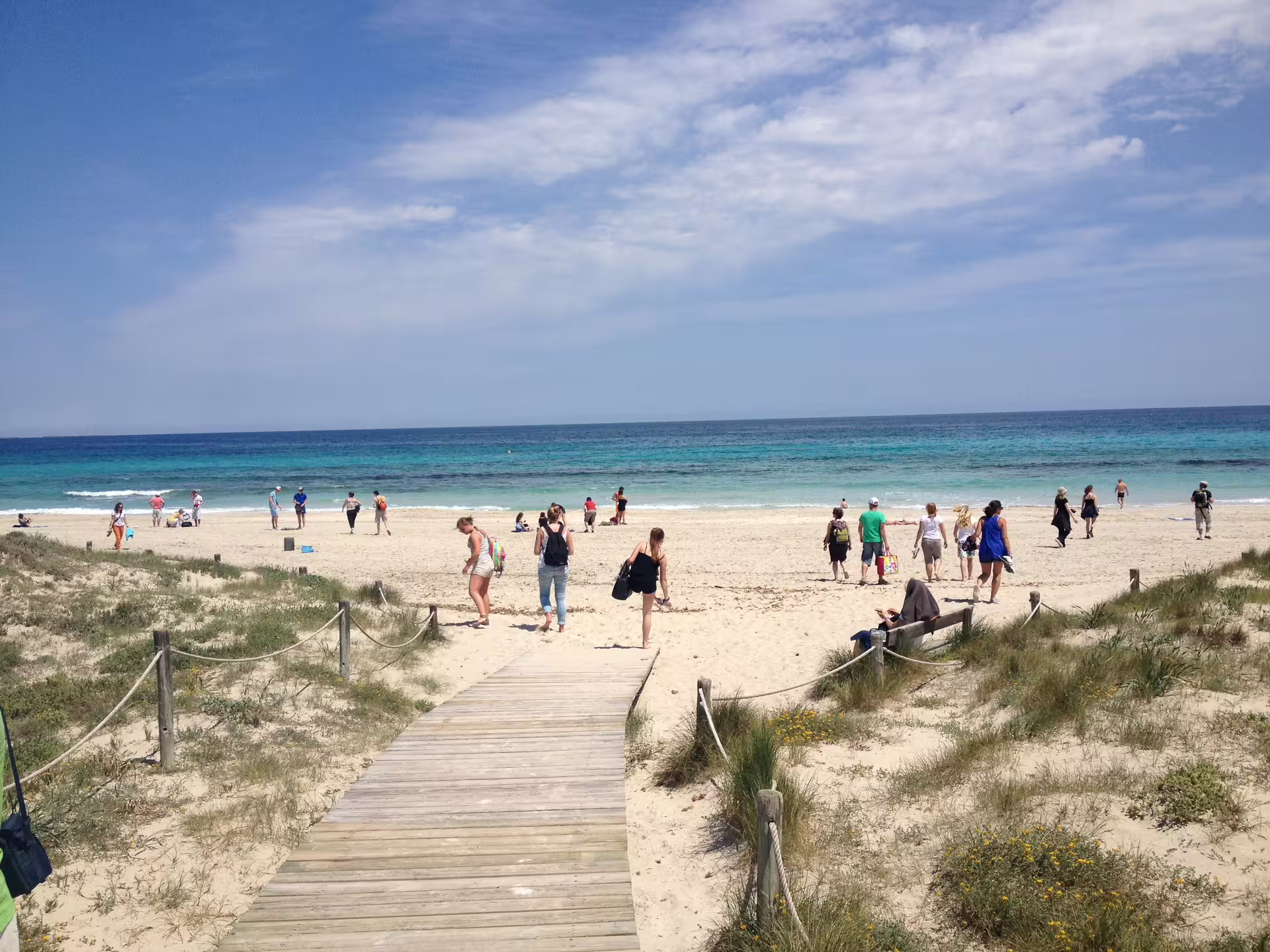 Wooden boardwalk to a sandy Formentera beach on Ibiza day trip with fast ferry transfers and turquoise sea