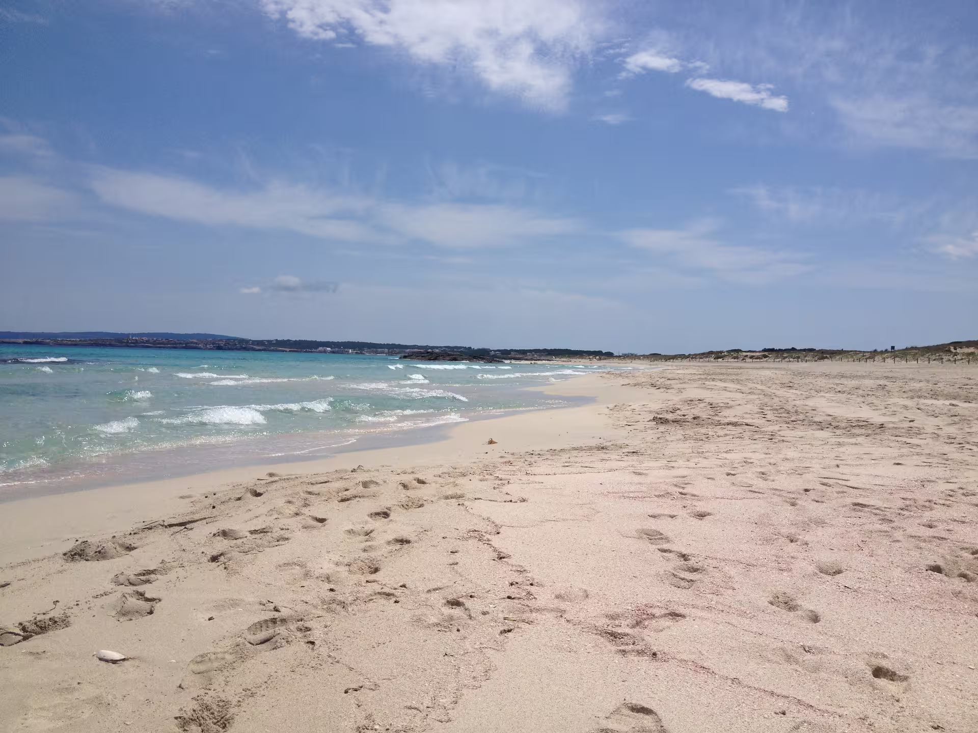 Wide sandy Formentera beach with turquoise waves, a highlight of Ibiza day trip fast ferry with transfers