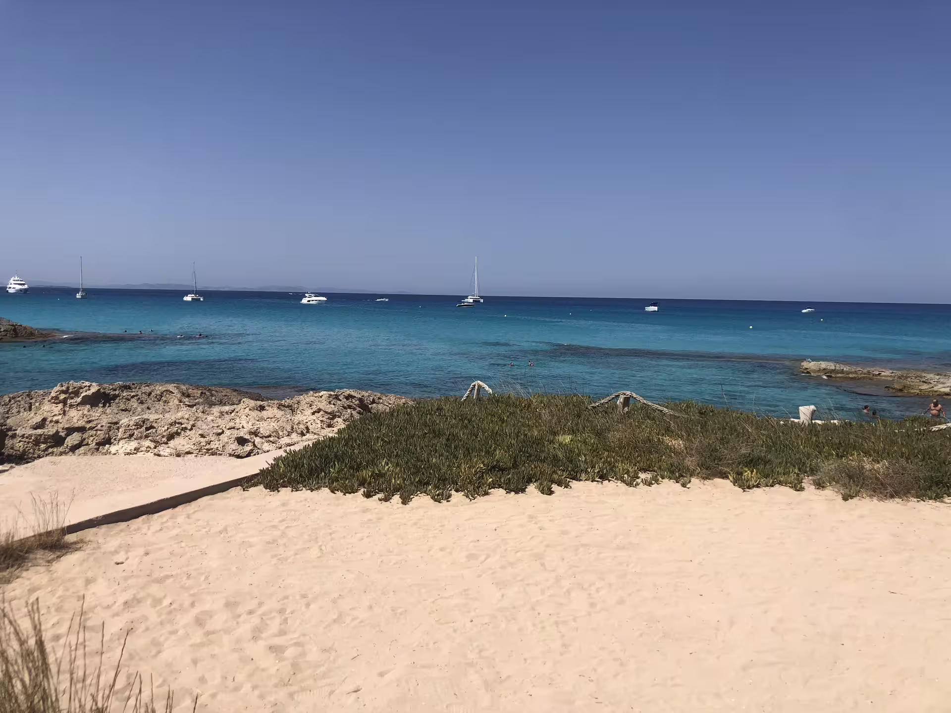 Ibiza bus tour stop at turquoise beach with sailboats offshore, perfect for fast ferry day trip with guide