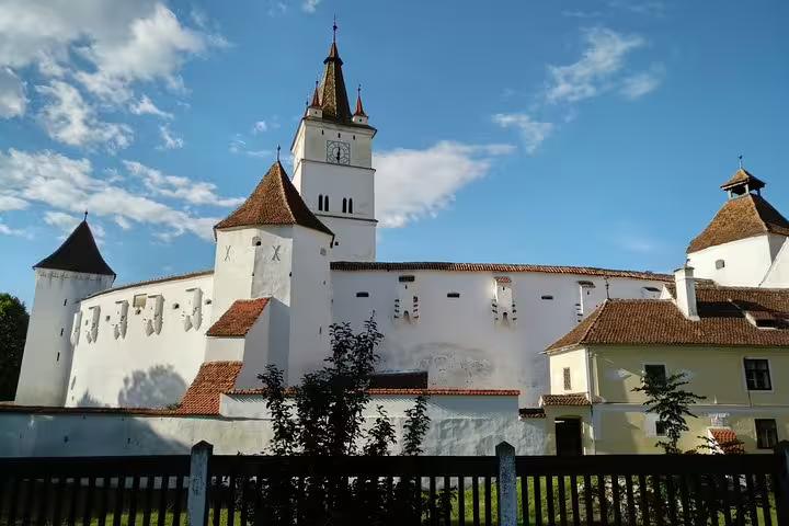 White fortified Saxon church with red-tiled roofs and defensive towers in Transylvania, Romania