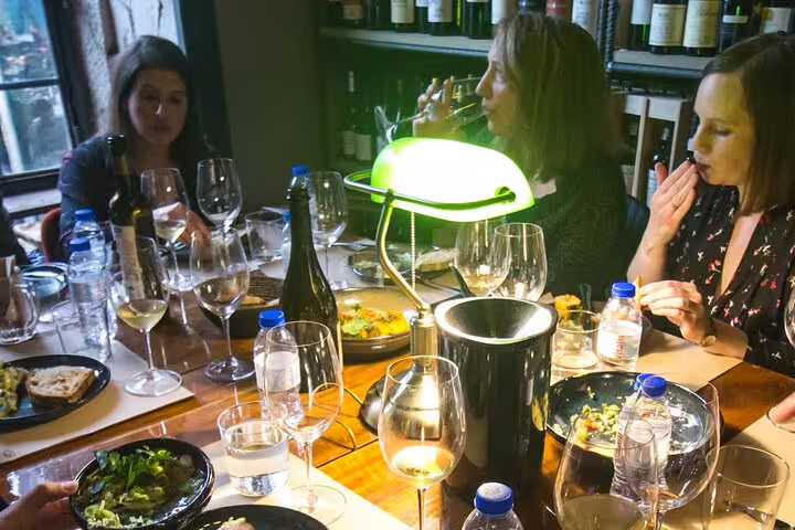 People enjoying a fortified wine tasting experience with a producer, surrounded by bottles and glasses in an intimate setting.