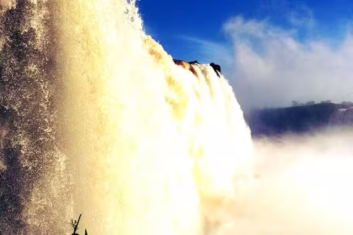 Majestic view of Foz do Iguaçu waterfalls cascading under a clear blue sky during a private panoramic flight tour.