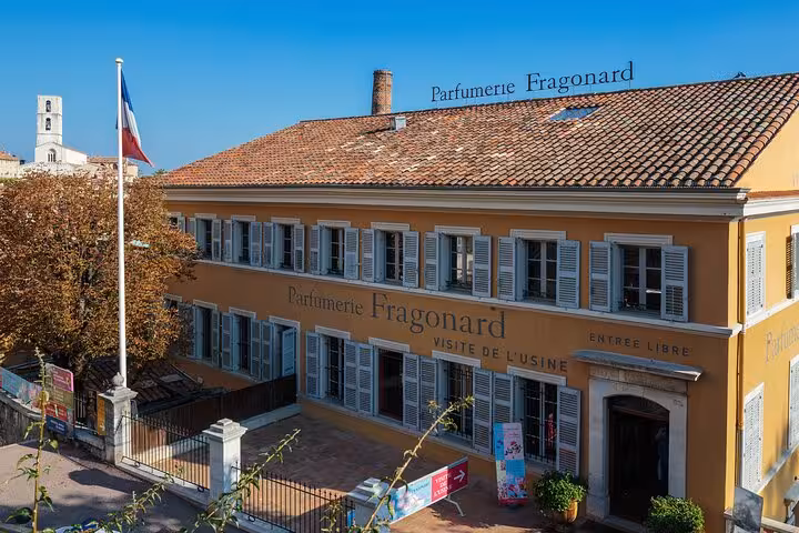 Exterior of Fragonard Perfume Factory in Provence, showcasing traditional architecture and French flag.