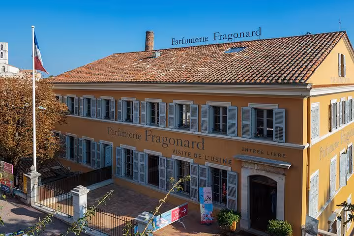 Exterior of historic Fragonard perfumery in the Provencal countryside, featuring classic architecture and French flag.