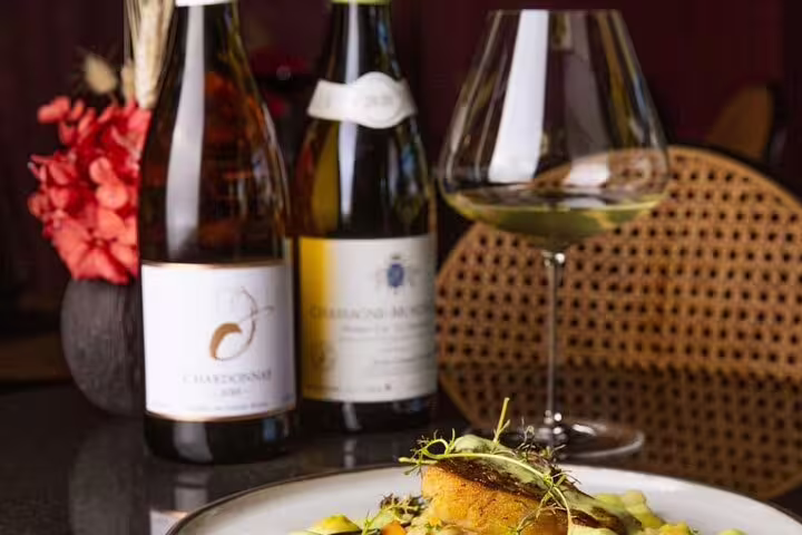 Gourmet dish paired with Chardonnay and wine glass on Franschhoek Tram Explorer Tour dining experience.