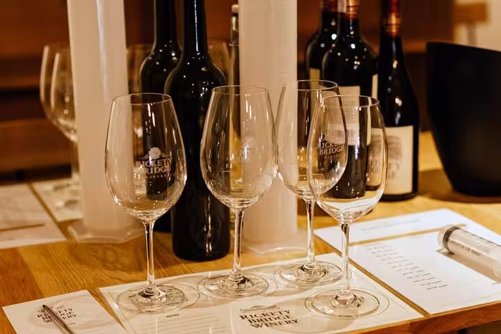 Wine tasting setup at a Franschhoek winery featuring empty glasses and assorted wine bottles on a wooden table.