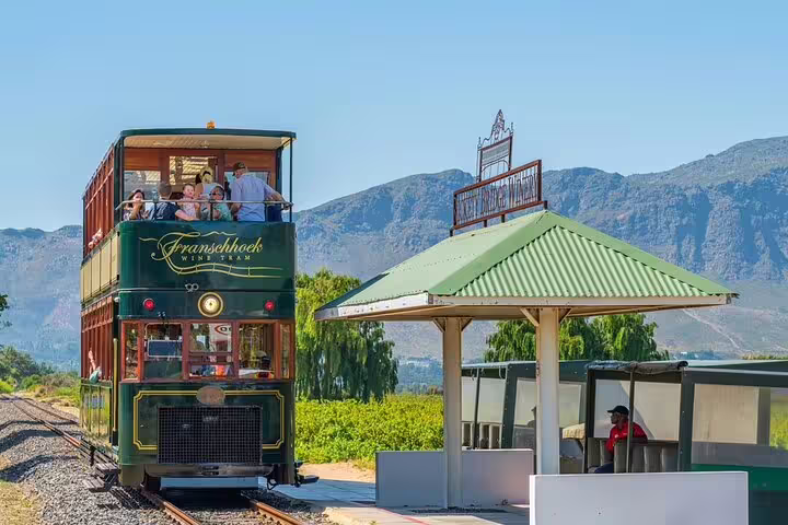 Franschhoek Wine Tram with tourists, offering vineyard views and a unique wine tasting experience in South Africa.