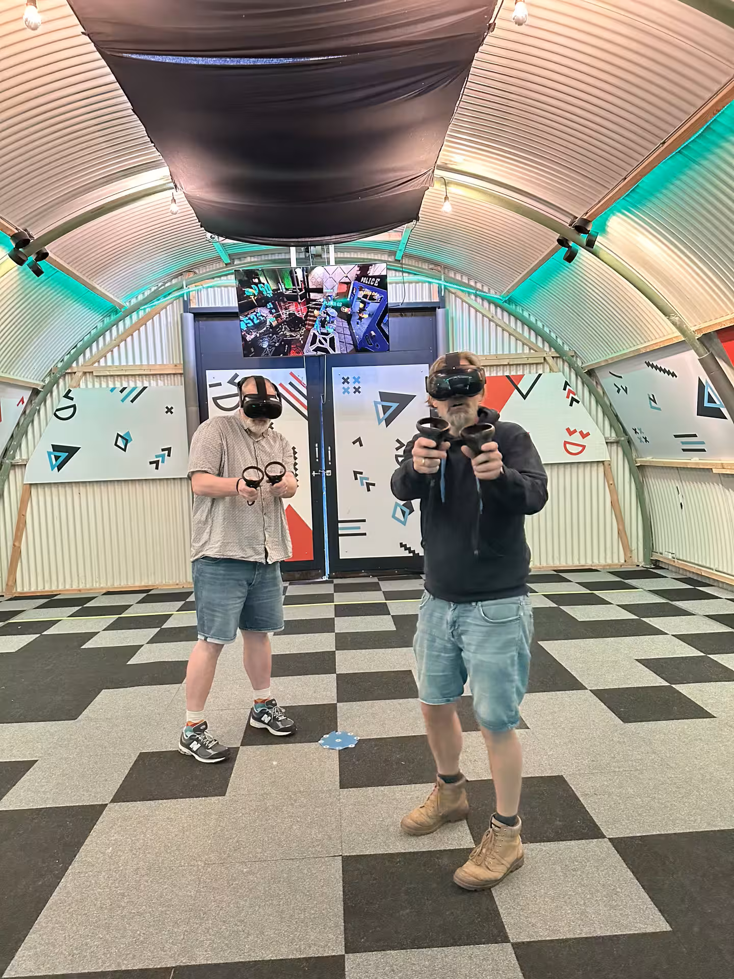 Two players in Amsterdam free roam VR arena wearing headsets and holding controllers for immersive multiplayer action