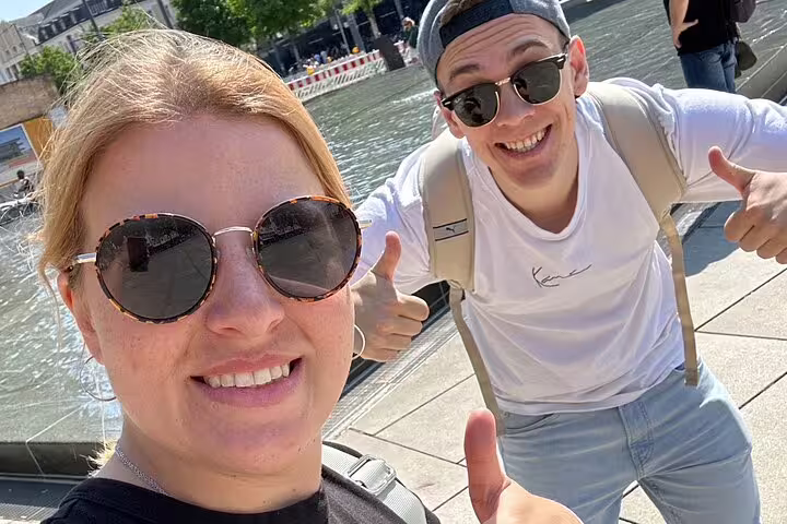 Smiling travelers by Freiburg fountain during a self-guided scavenger hunt and sights tour in Breisgau