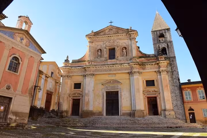 Historic church with ornate facade and bell tower in a picturesque French Alps village under clear skies.