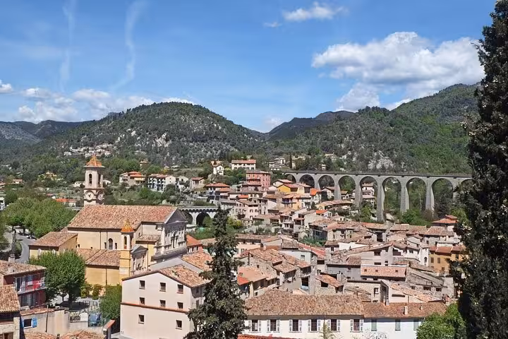 Scenic view of a quaint village near the French Alps with lush hills and a historic viaduct.