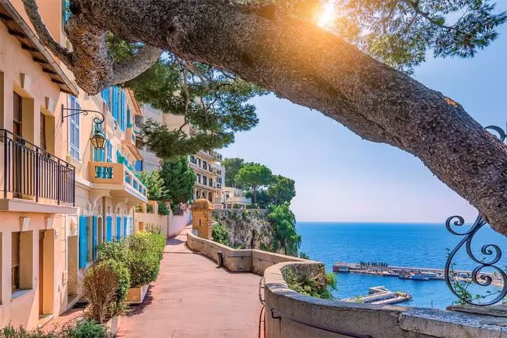 Serene coastal path in the French Riviera with colorful buildings and a view of the sparkling Mediterranean Sea.