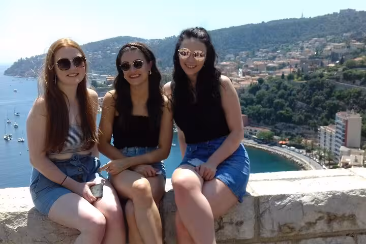 Three friends posing with a stunning coastal view of the French Riviera, showcasing the beauty of the region.