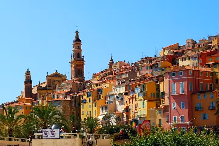 Colorful hillside village in the French Riviera with bell towers and palm trees, a highlight of a private tour.