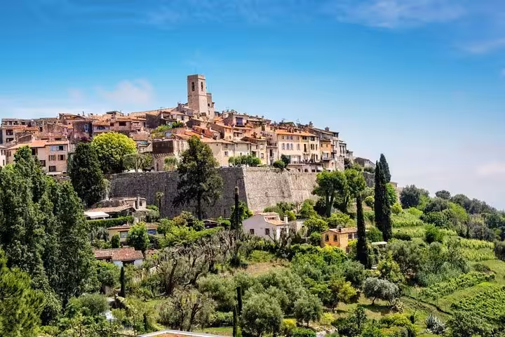 Charming hilltop village in the French Riviera surrounded by lush greenery under a clear blue sky.