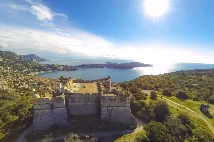 Aerial view of a historic fort overlooking the Mediterranean coast on a sunny day in the French Riviera.