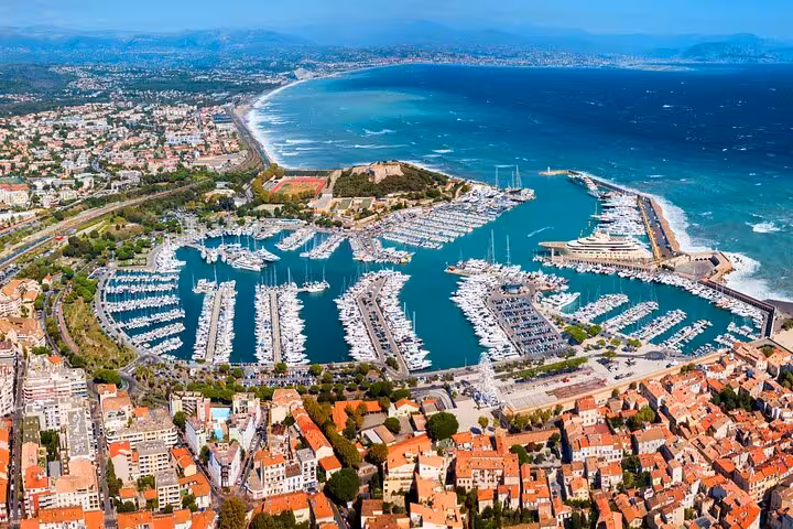 Aerial view of a picturesque marina in the French Riviera, showcasing yachts and coastal scenery.