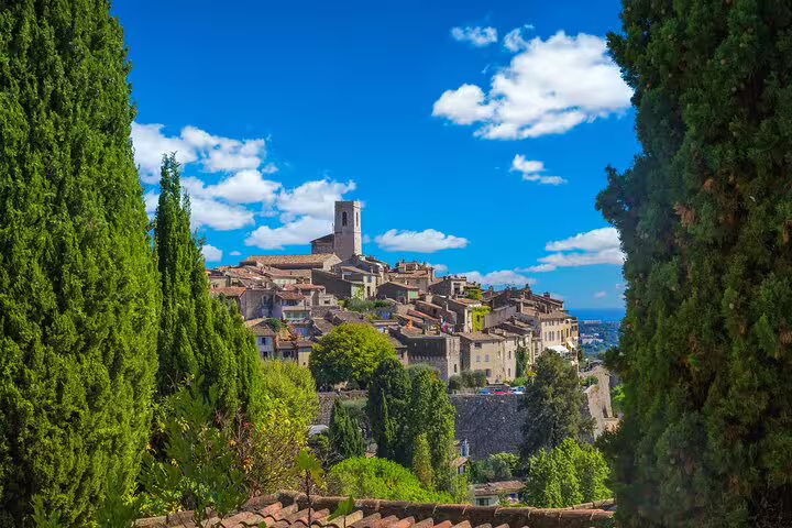 Hilltop medieval village in the French Riviera near Nice, framed by cypress trees under a bright sky