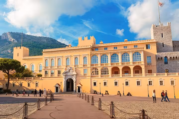 The majestic facade of a grand palace set against a mountainous backdrop in the French Riviera.