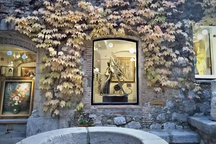 Charming art gallery with ivy-covered stone walls in a French Riviera village, showcasing local sculptures.