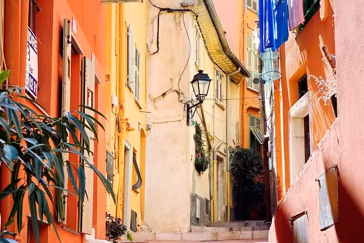 Vibrant narrow alley in a French Riviera village with colorful facades and traditional architecture.
