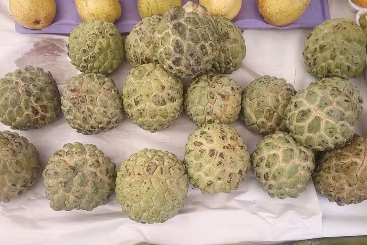 Display of fresh cherimoyas on a market stall, highlighting exotic fruits on Rio Tropical Fruit Tour.
