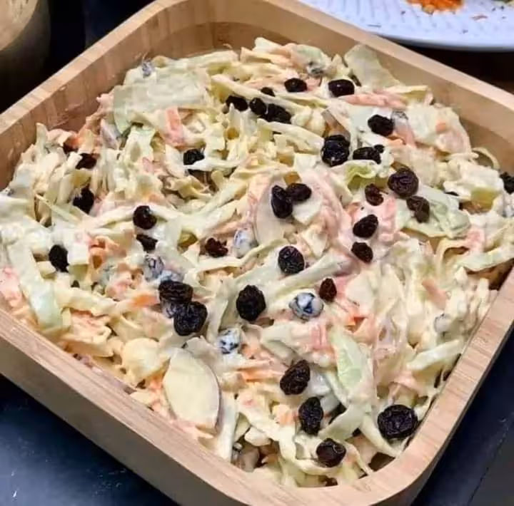 Fresh coleslaw with raisins in a wooden bowl, a tasty side dish on your one-week Luxor dining experience.