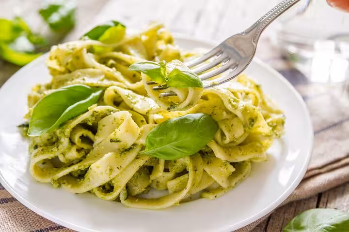 A plate of fresh pasta with vibrant basil pesto sauce, ready to enjoy after a cooking class in Rome.