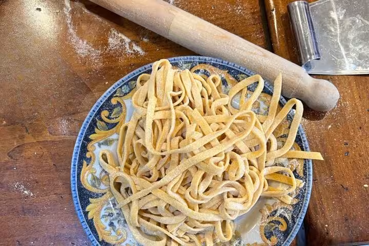 Freshly made pasta on a decorative plate with rolling pin, perfect for a hands-on cooking class in Rome.