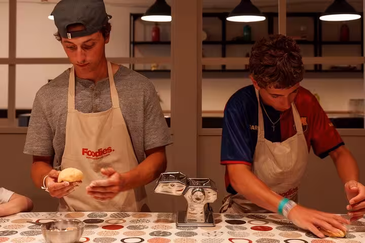 Participants making fresh pasta in a hands-on workshop in Barcelona, using traditional techniques and pasta machines.