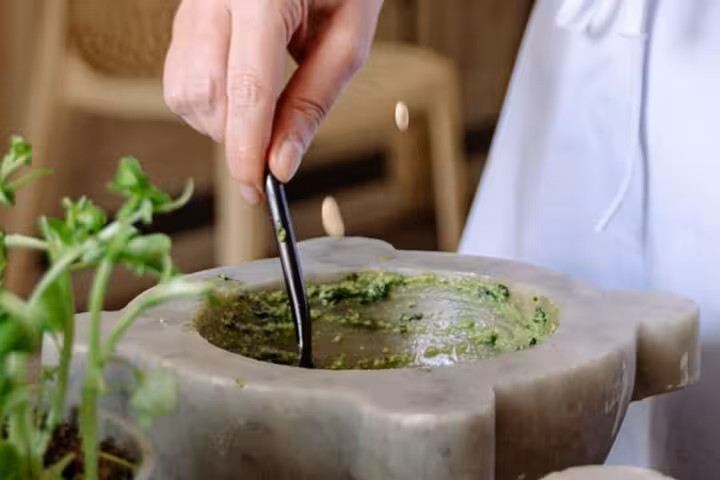 Hand mixing fresh pesto in a traditional mortar during Chiavari food tour with local ingredients.