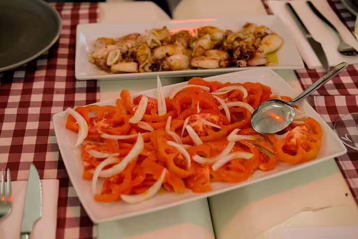 Colorful seafood and fresh tomato onion salad on a checkered tablecloth, part of Only Fish Market Tasting Tour from Sea to Table.