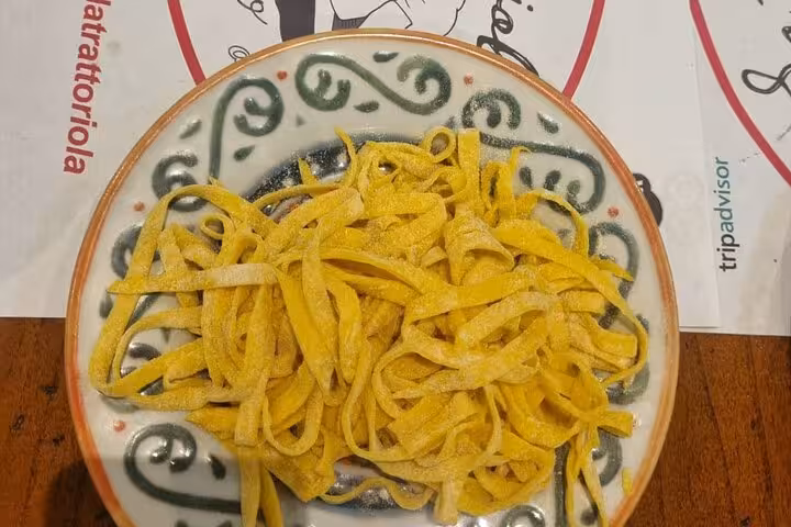 Close-up of freshly made tagliatelle pasta on a decorative plate, highlighting authentic Italian culinary skills.