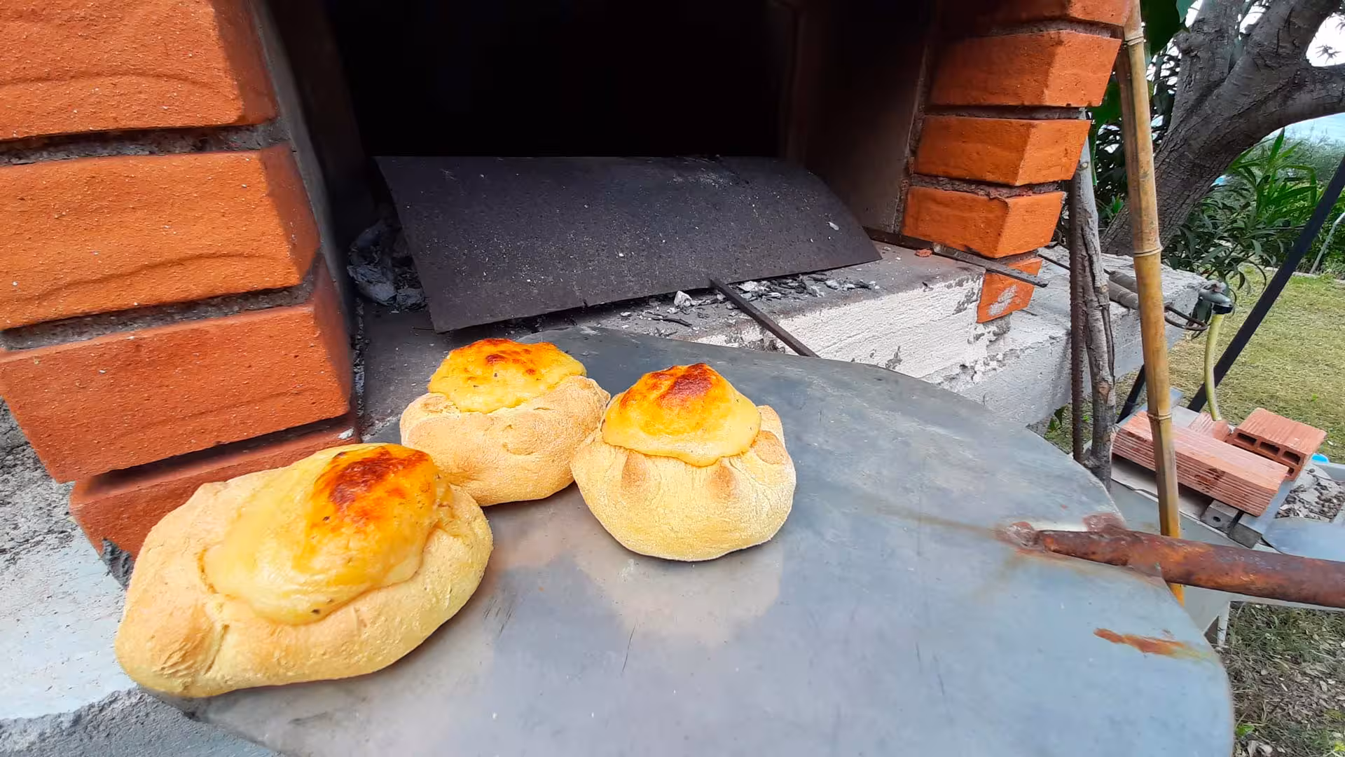 Freshly baked bread cooling outside a rustic brick oven on a Sardinian farm during a tasting tour in Arzana.