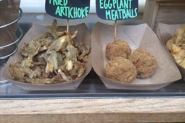 Close-up of fried artichoke and eggplant meatballs at a food stall in Rome's Testaccio market.